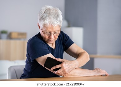 Woman Testing Glucose Level With Continuous Glucose Monitor On Mobile Phone