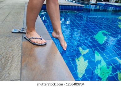 Woman testing water temperature of Pool with her foot - Powered by Shutterstock
