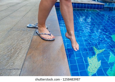 Woman Testing Water Temperature Of Pool With Her Foot