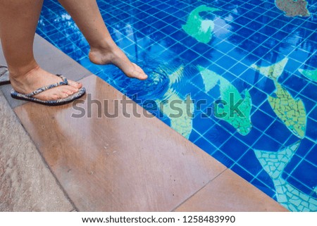 Woman testing water temperature of Pool with her foot