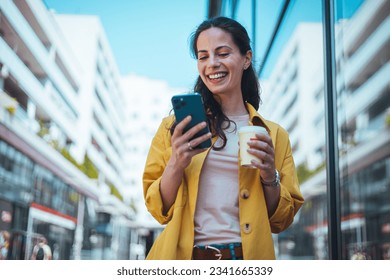 Woman texting and drinking coffee outdoors. Artificial intelligence and communication network concept.Beautiful young woman using a smartphone. 