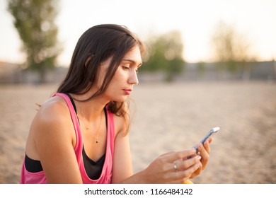 woman texting on smart phone on the beach during sunset - Shutterstock ID 1166484142