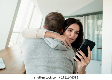 Woman texting other men when embracing her boyfriend. Lies will always pop up concept. Man trusts his wife but she deceives him. Cheating concept. Woman looking in her smartphone while hugging man