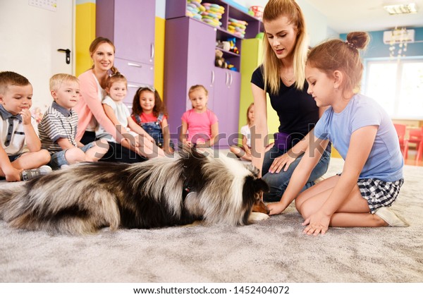 Woman\
and therapy dog working with kids in the preschool\
