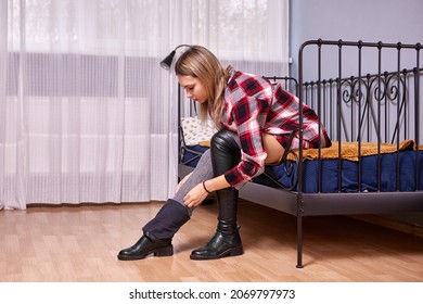 Woman In Thigh High Boots Sits On Metal Bed In  Bedroom.