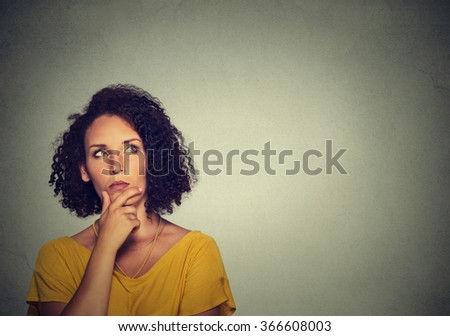 Woman thinking dreaming has many ideas looking up isolated on gray wall background.