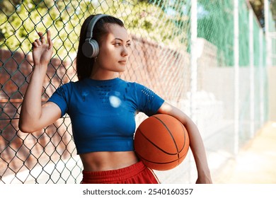 Woman, thinking and outdoor by fence as basketball player or athlete for challenge or exercise. Female person, planning and headphones in competition, match or game for idea, sport or training advice - Powered by Shutterstock