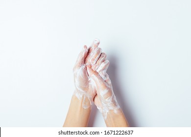 Woman thoroughly washing her hands with soap, close-up on white background, top view.