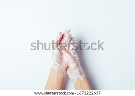 Woman thoroughly washing her hands with soap, close-up on white background, top view.