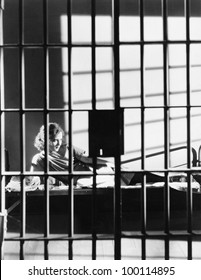 Woman Through Bars Of Jail Cell