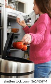 Woman Throwing Away Out Of Date Food In Refrigerator