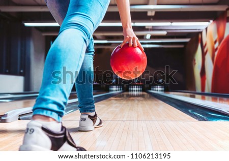 Woman throwing ball in bowling club. View from behind