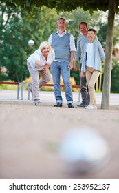 Woman Throwing Ball While Playing Boule Game With Senior People