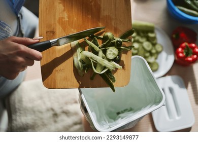 Woman throwing organic food waste in a compost bin. Female person recycling compostable leftovers in a bokashi container  - Powered by Shutterstock