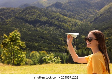 Woman Throwing Paper Plane In Mountains On Sunny Day. Space For Text