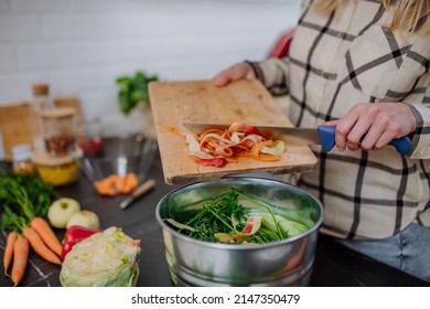 Woman throwing vegetable cuttings in a compost bucket in kitchen. - Powered by Shutterstock