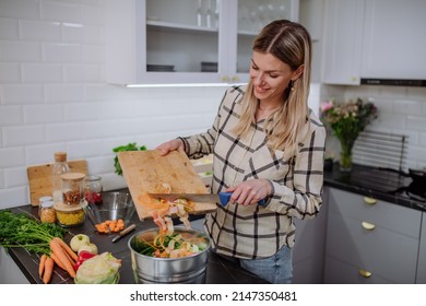 Woman throwing vegetable cuttings in a compost bucket in kitchen. - Powered by Shutterstock