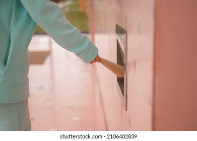 A Woman Throws A Kraft Paper Bag Down A Garbage Hole In A Cafe Wall.