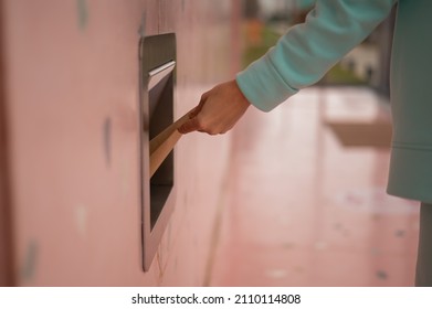 A Woman Throws A Kraft Paper Bag Down A Garbage Hole In A Cafe Wall.