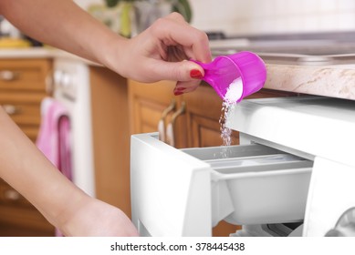 Woman throws laundry detergent into the washing machine close-up.