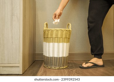 woman throws rubbish in organic waste bin.  The trash can is made of woven bamboo.  plastic free and environmentally friendly waste basket.