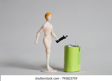 Woman Throws Tiny Man In A Trash Can.  Concept Of Ending Bad Relationships Or Ditching A Bad Boss. Breakup Or Divorce. Concept Of Employment Or Romantic Rejection. Frustration With Online Dating. 