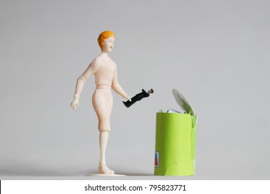 Woman Throws Tiny Man In A Trash Can.  Concept Of Ending Bad Relationships Or Ditching A Bad Boss. Breakup Or Divorce. Concept Of Employment Or Romantic Rejection. Frustration With Online Dating. 