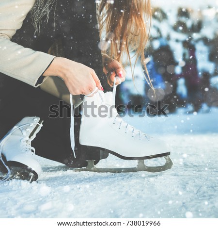 Woman tie shoelaces at figure skates at ice rink close-up, ice skating