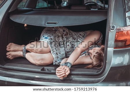 
Woman with tied hands inside car trunk - kidnapping concept