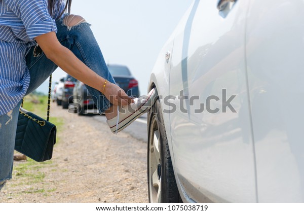 Woman tied a shoe\
string on a car wheel.