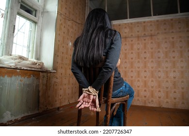 A Woman Tied Up Sits On A Chair In An Abandoned Room