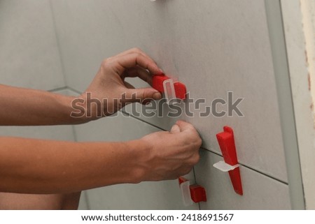 Woman tiling bathroom walls. Flat wall plastic tile leveling system. Process of installation of tiles in the bathroom. DIY home improvement.	