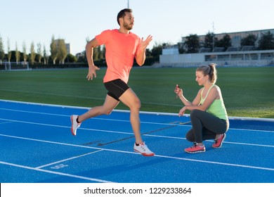 Woman is timing to runner with chronometer at the end of run in a race track. Competition. - Powered by Shutterstock