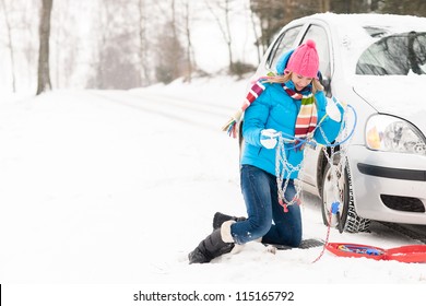 Woman with tire chains car snow breakdown winter problematic young