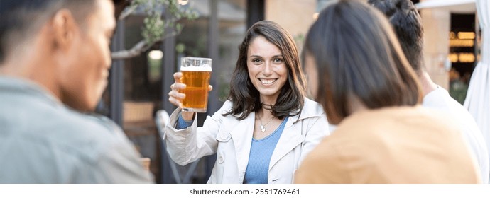 Woman toasting with friends at an outdoor gathering. Happy young adults enjoying drinks and socializing in a relaxed setting - Powered by Shutterstock