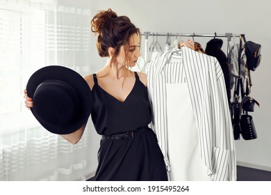 The woman in the toilet in the room chooses what to wear. Choice of clothes, wardrobe. Fashion style