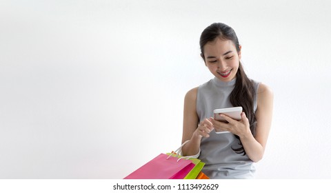 Woman Took A Contactless Payment. Lady Buying Online With A Smart Phone. Happy Woman Paying By Smartphone Or Tablet. Girl On White Background. Shopping Bag On Hand. Asian Women.