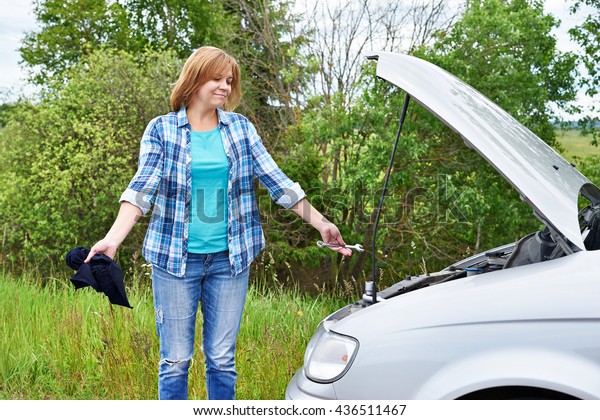 Woman with tools near her\
broken car