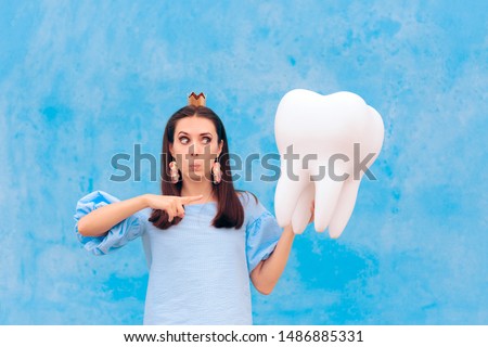 Woman in Tooth Fairy Costume Holding Big Molar. Funny princess holding an oversized fallen baby tooth 
