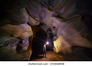 Woman with Torch lamp exploring huge ancient fortress cave