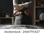 Woman tossing pizza dough at table in kitchen, closeup