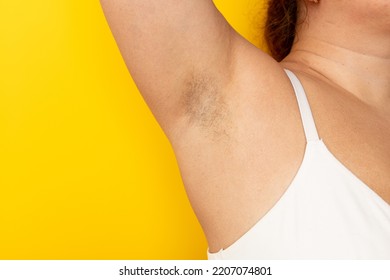 Woman touch hairy underarms with hand closeup, free copy space, yellow background. Raised arm with armpit hair. Female beauty trend, freedom, feminism, body positive, naturalness. Hygiene concept. - Shutterstock ID 2207074801