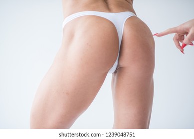 Woman Touches The Buttocks Of A Female Body Builder In White Lingerie Against A White Wall. Female Sports Buttocks Touches The Female Hand