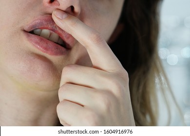 woman touches the scabs and bruises on the filled lips, complications after lip augumentation, closeup - Shutterstock ID 1604916976