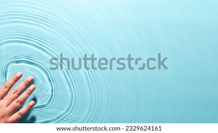 Woman touching by hand finger on purity transparent water surface on blue background copy space. People lifestyle medical hygiene nature protective wellness. World environment day and World water day