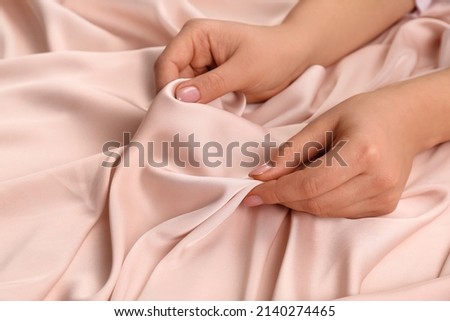 Woman touching delicate beige fabric, closeup view
