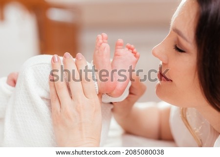 Woman touching feet of newborn baby with hands