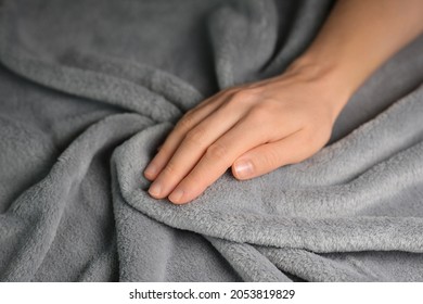 Woman touching grey blanket, close up. Close up of hand touching soft blanket. Gentle and fluffy blanket between fingers.