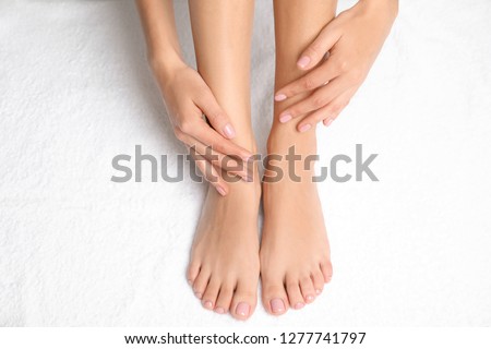 Woman touching her smooth feet on white towel, closeup. Spa treatment