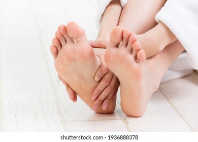 A woman is touching her sole.